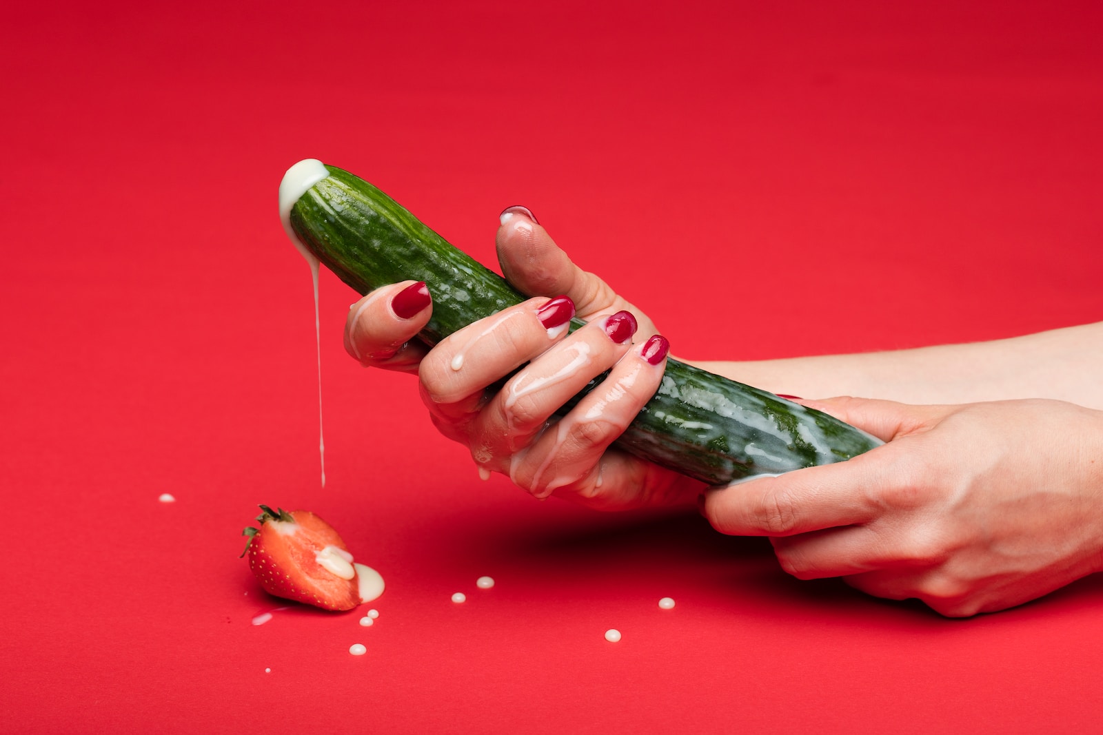 person holding green cucumber on red table